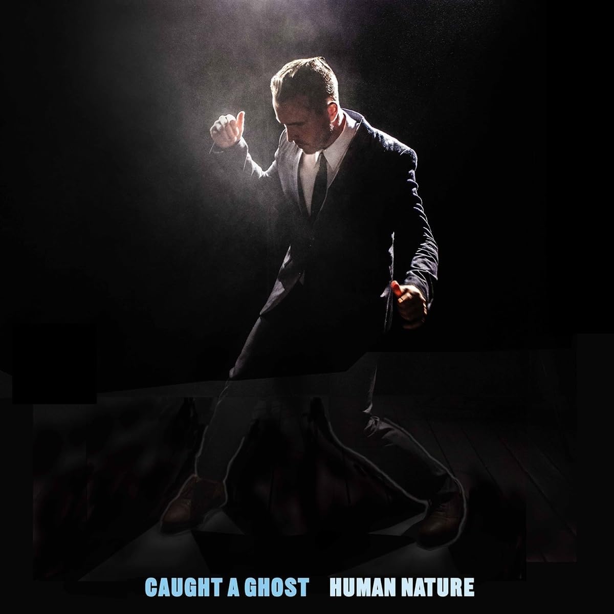 Man in suit mid-motion against a dark, smoky background; album cover.