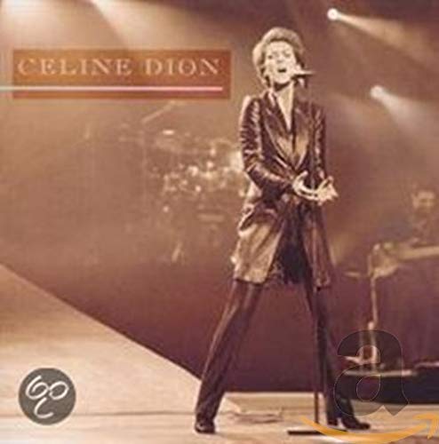 Céline Dion performing live on stage in a black suit.