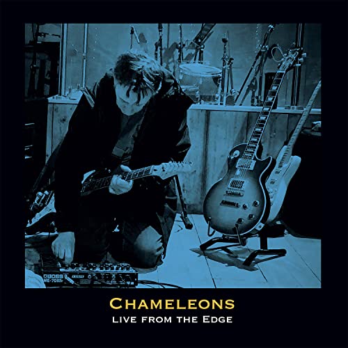 Musician playing electric guitar in a dimly lit studio, album cover.