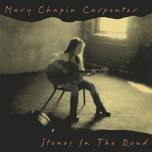 Mary Chapin Carpenter sits playing guitar in a sunlit, rustic room.