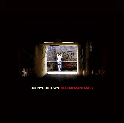 A person stands in a dark graffiti-covered tunnel, illuminated by light from the end.