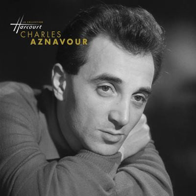 Black and white portrait of Charles Aznavour, resting chin on hands.