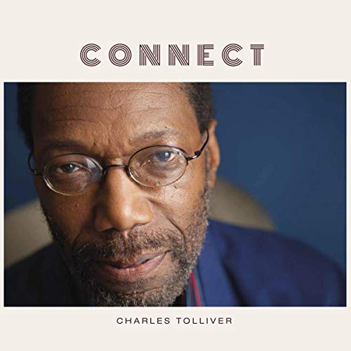 The image is a vinyl album cover featuring a man with glasses and a blue jacket. For accessibility purposes, a suitable alt text could be: "Vinyl album cover with a man wearing glasses."