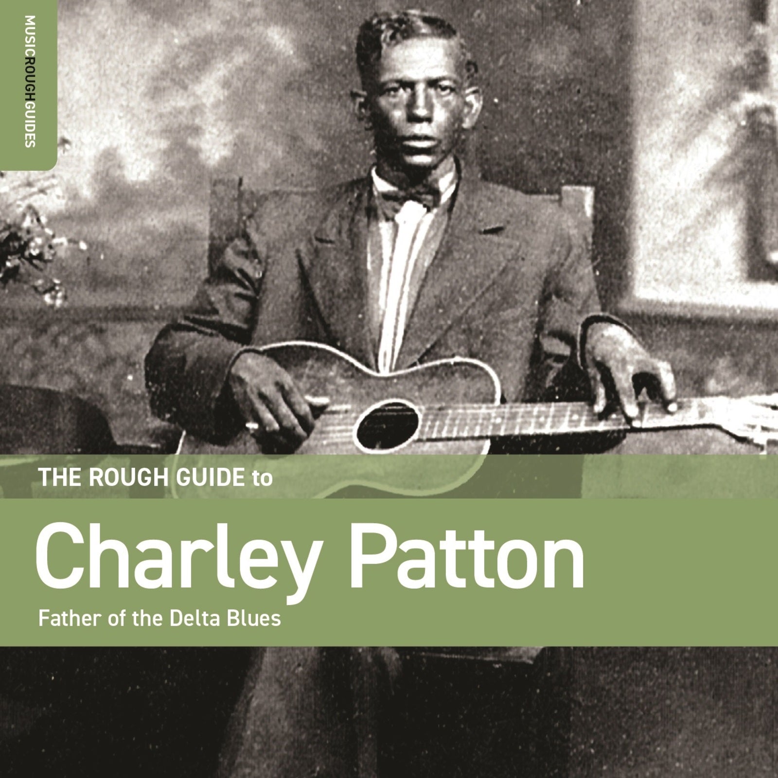 Black and white portrait of Charley Patton with a guitar.