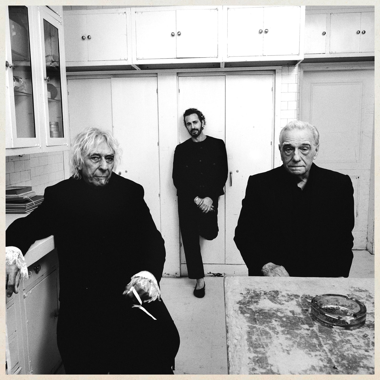 Black and white photo of three people in a kitchen setting.