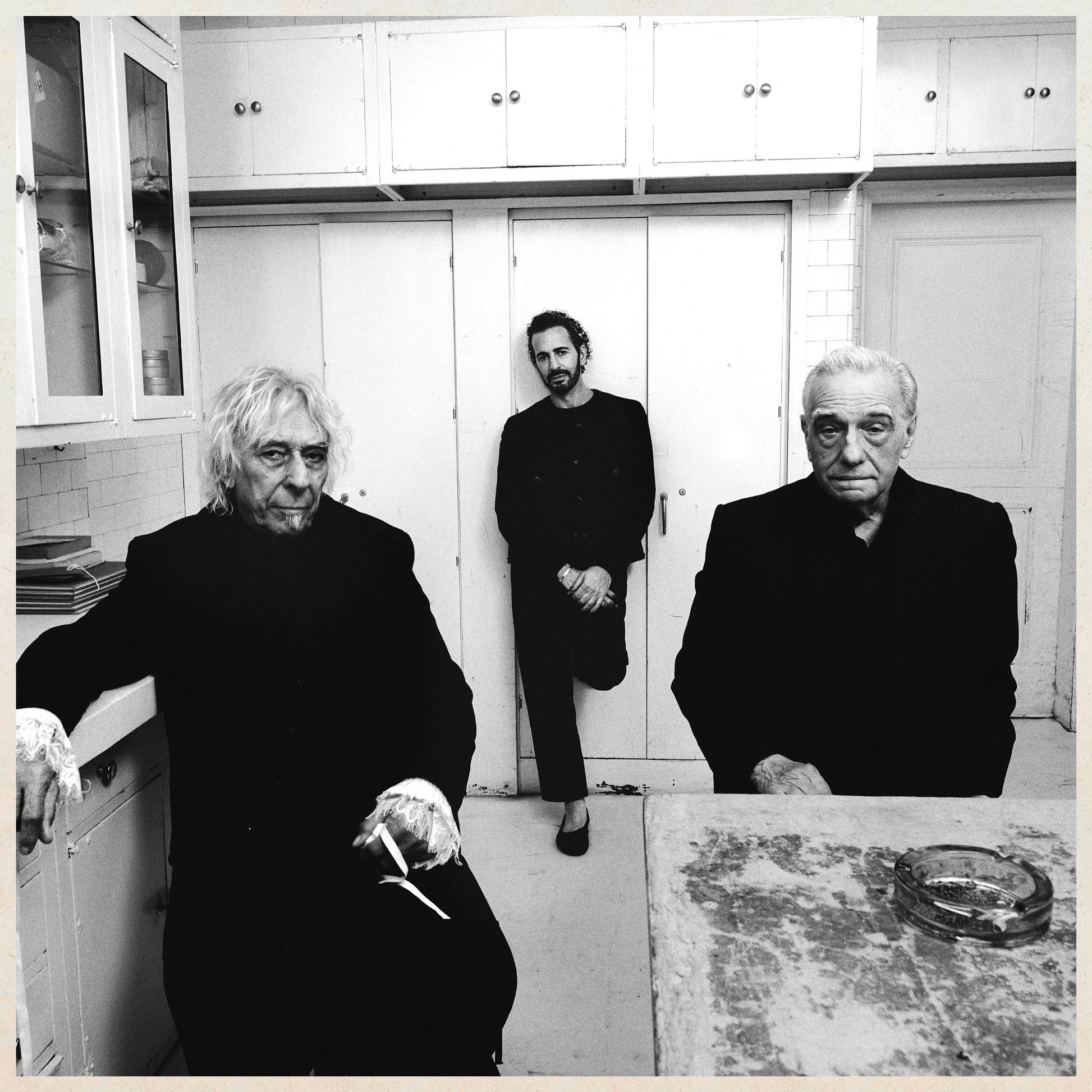 Black and white photo of three people in a kitchen setting.