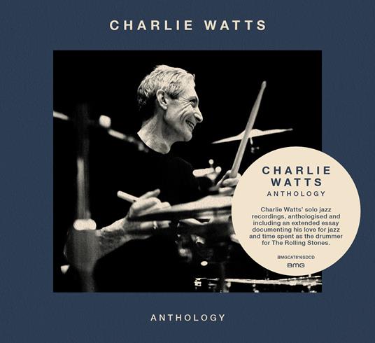 Charlie Watts playing drums in a black and white photo on a blue background.