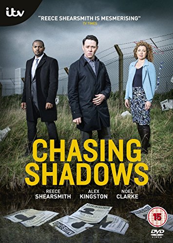 Three actors stand in a field with missing person posters on the ground below.