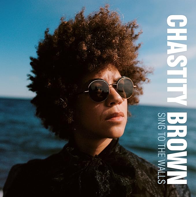 Chastity Brown portrait with afro, sunglasses, and album title text.