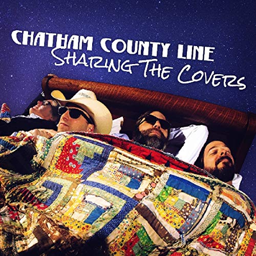 "Album cover: three men in bed under a quilt, against a starry night sky."