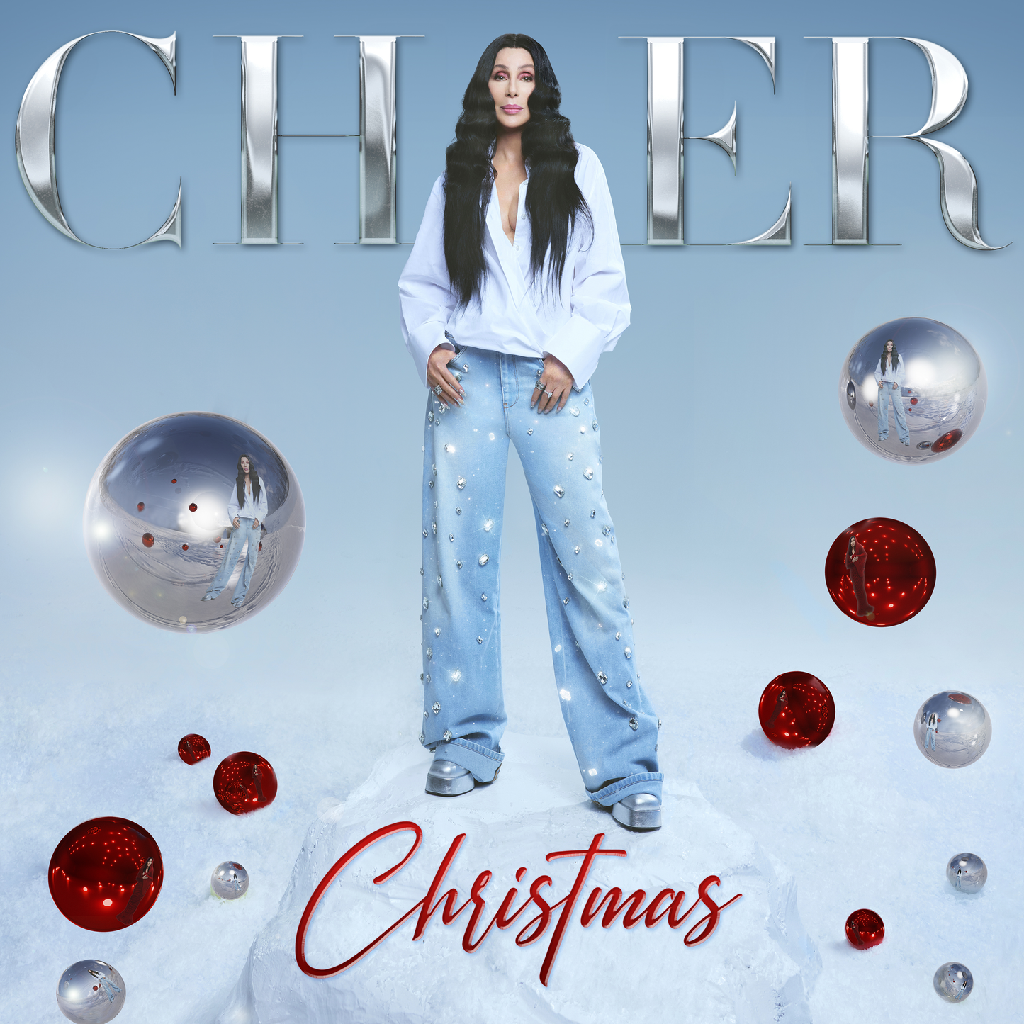Cher poses in a white suit amidst ornaments on a snowy background.