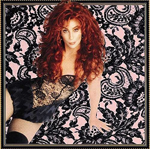 Cher with long red hair wearing a black lace bodysuit against a pink background.