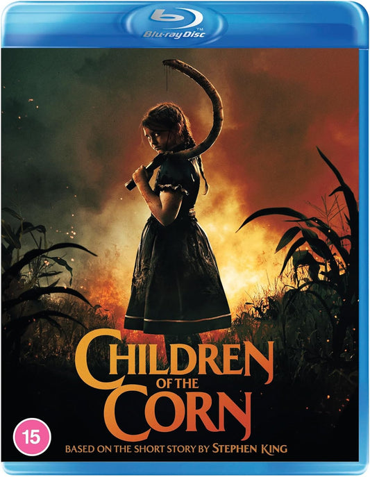 A girl in a dark dress holds a sickle standing before a burning cornfield.