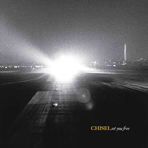 Grainy black and white airport runway at night with bright lights.
