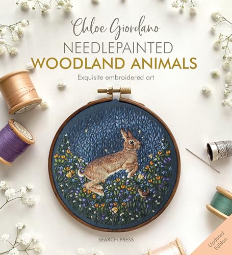 Embroidery hoop featuring a rabbit in a floral meadow, surrounded by thread spools.