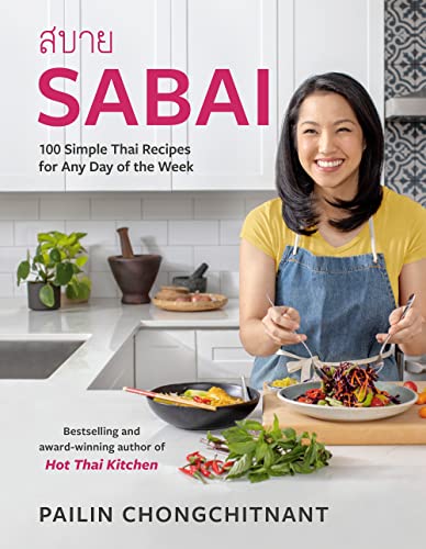 Cookbook cover featuring a woman with Thai food in a kitchen.