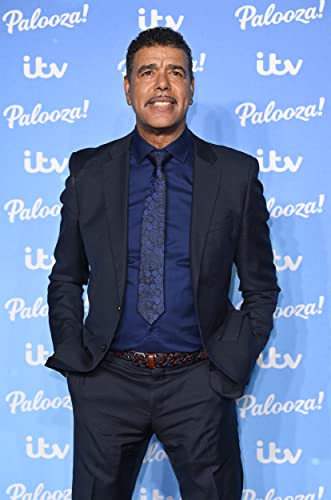 Kammy, a man in a suit and tie, poses against a blue backdrop.