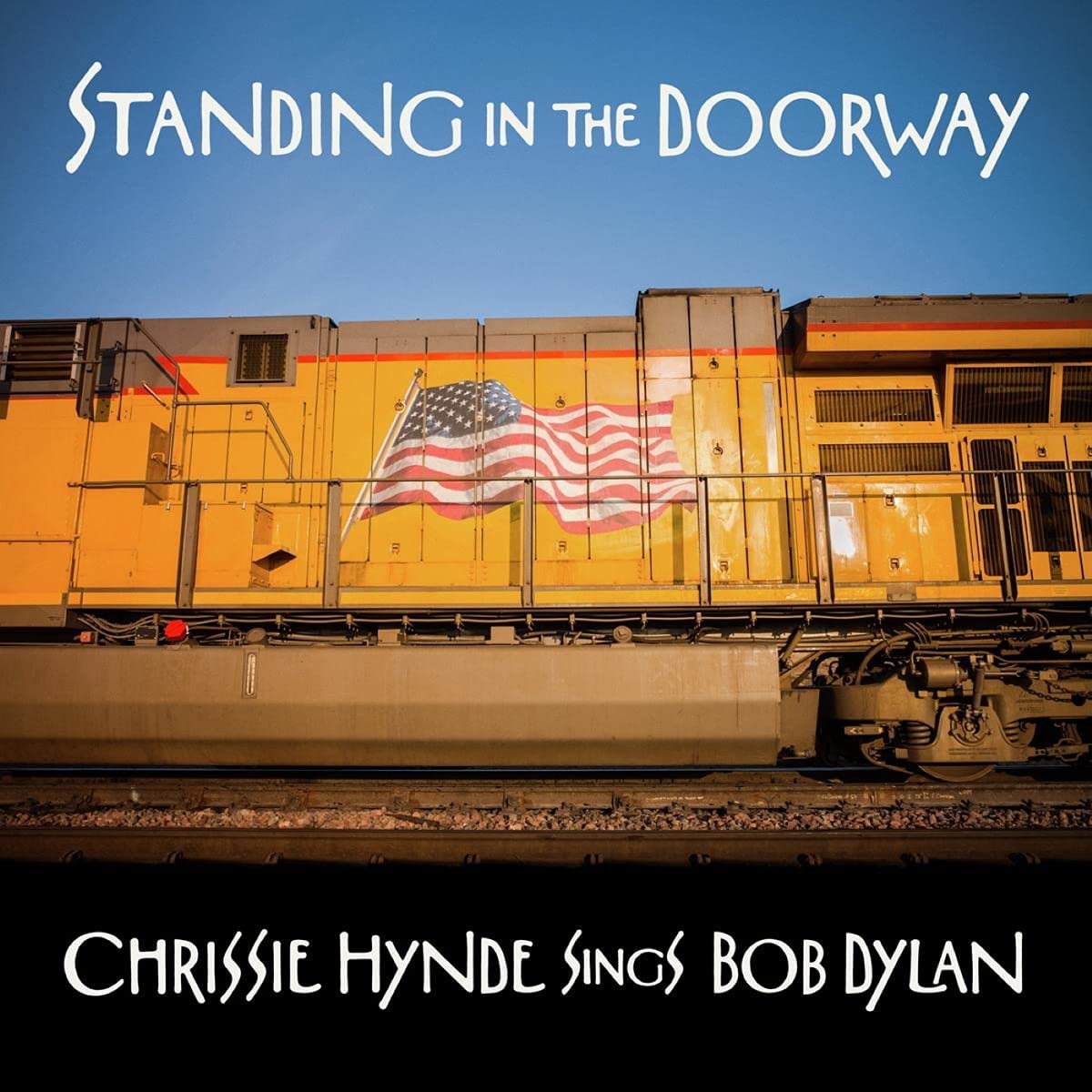 Album cover with yellow train and American flag against a blue sky.