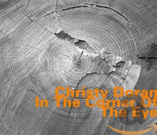 CD cover with wood grain texture and orange text: "In The Corner Of The Eye".