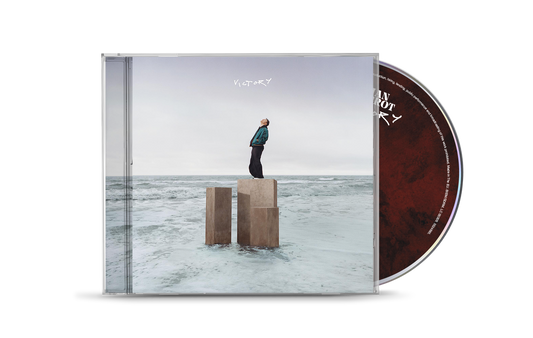 CD case for Cian Ducrot’s “Victory,” featuring a man on pillars by the sea.