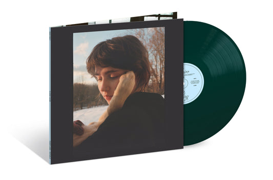 Dark green vinyl record next to its album cover featuring a person's portrait.
