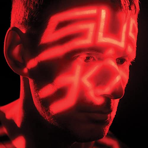 Close-up of a man’s face with red geometric light projections.