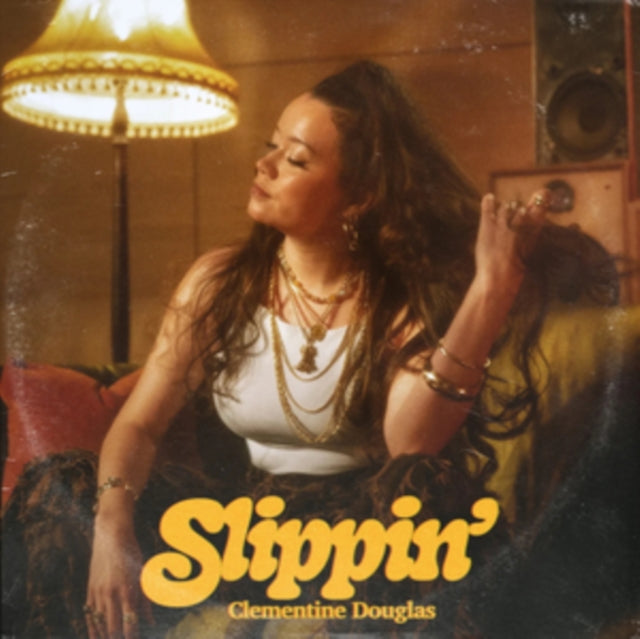 Clementine Douglas sits on a couch under a lamp on this album cover.