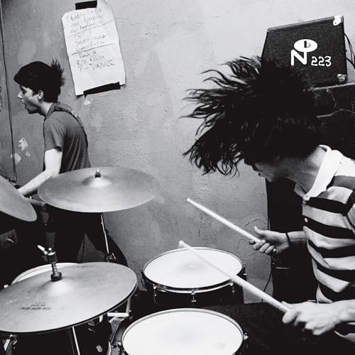 Black and white photo of musicians playing drums with energetic movement.