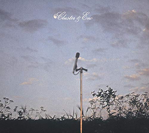 A microphone stand stands in a field against a twilight sky with the moon.