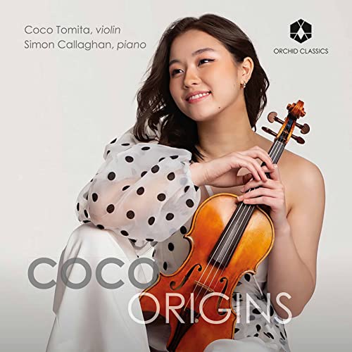Coco Tomita, a violinist, holding a violin and smiling at the camera.