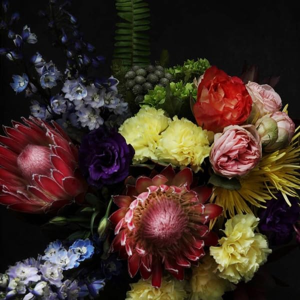 Dark, moody still life of a colorful, diverse flower arrangement.
