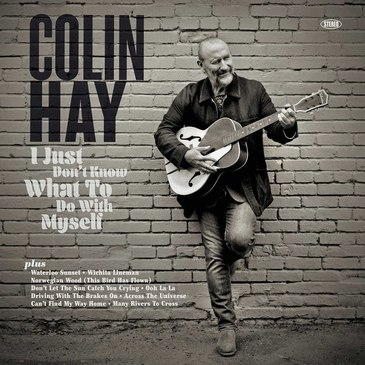 "Colin Hay album cover with man holding guitar against a brick wall."