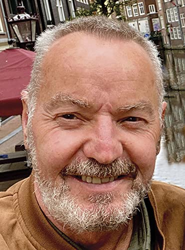 Close-up portrait of a smiling, older man with grey beard and mustache.