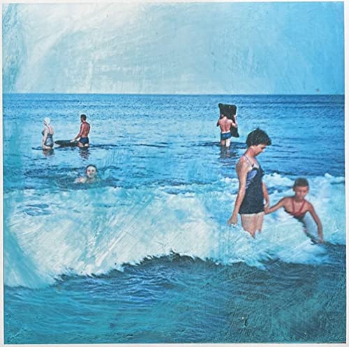 People swimming in the ocean with a large wave in the foreground.