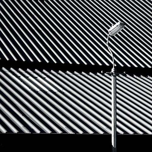 Black and white image of corrugated metal and a security light.