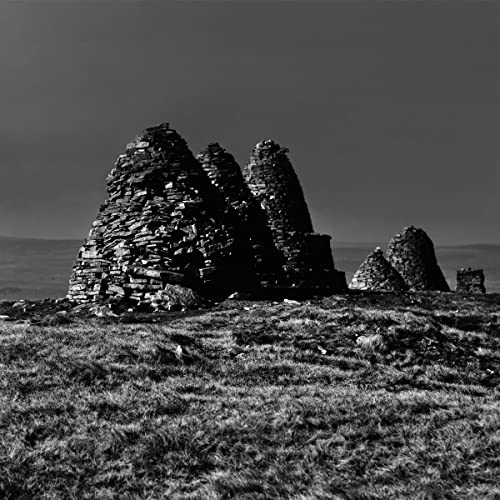 Black and white photo of crumbling stone structures in a field.