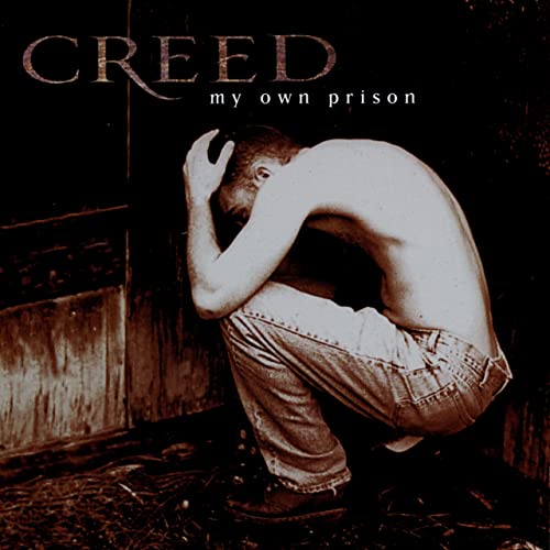 Album cover for Creed’s “My Own Prison” featuring a man crouching in despair.