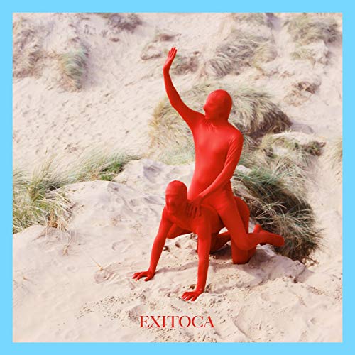 Two figures in red suits on a sandy dune, one raising an arm.