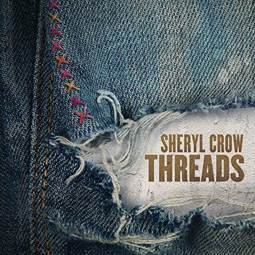Close-up of blue denim fabric with colorful stitching and a frayed, torn patch.