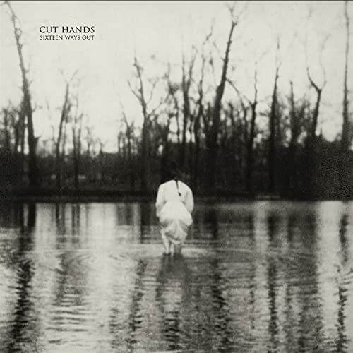 Black and white album cover with a lone figure in a watery landscape.