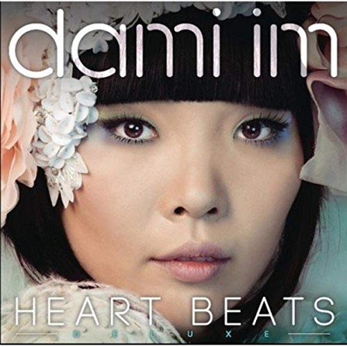 Close-up portrait of Dami Im with floral hair accessories and the album title text.