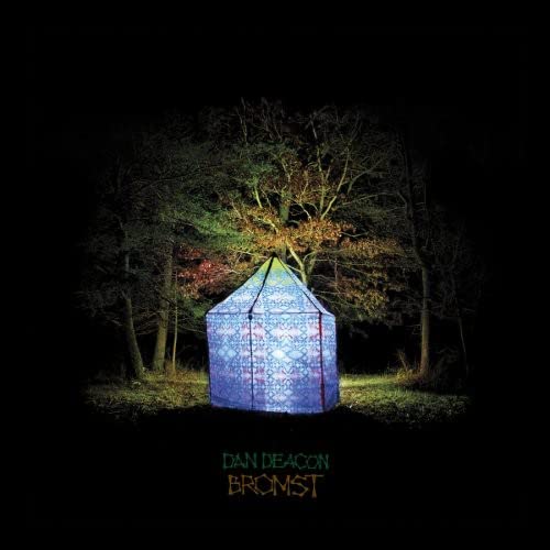 An illuminated patterned tent stands in a dark forest at night.
