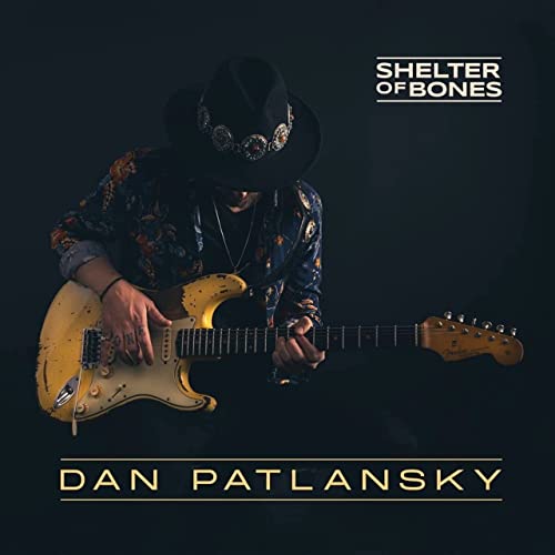 Dan Patlansky in a hat playing a yellow electric guitar.