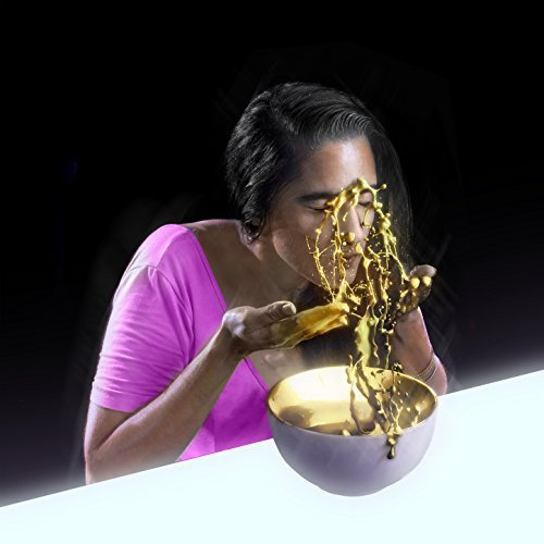A person in a pink shirt splashes gold liquid from a bowl onto their face.