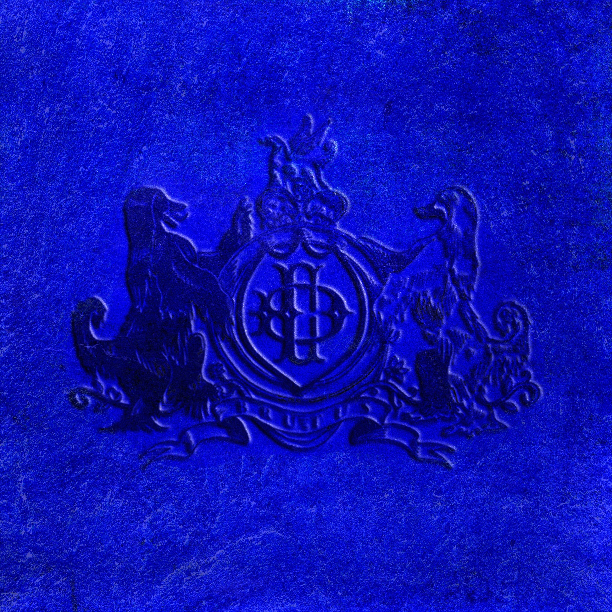 Blue CD cover for Daniel Caesar’s “NEVER ENOUGH” with embossed crest.