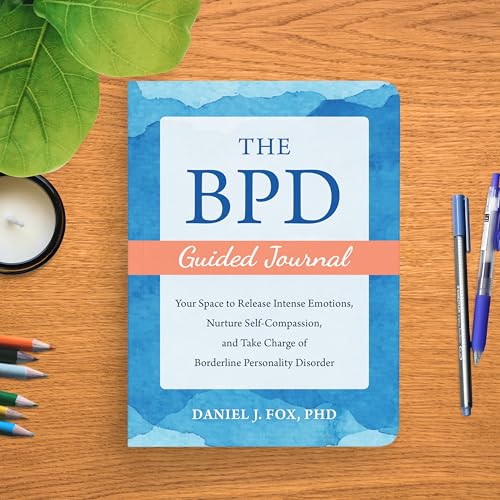 The BPD Guided Journal book cover on a wooden desk with pens and leaves.