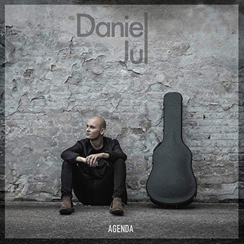Album cover for Daniel Jul’s “Agenda” featuring a man and guitar case.