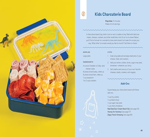 A bento box filled with snacks next to a cookbook page for charcuterie boards.