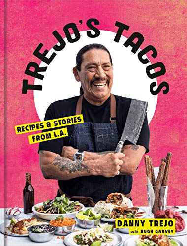 Danny Trejo smiles on the cover of his taco recipe book with food.