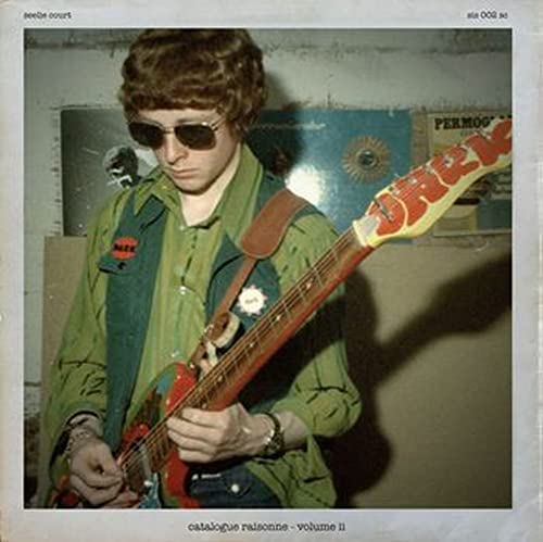 Man with sunglasses playing a red and yellow Rickenbacker bass guitar.